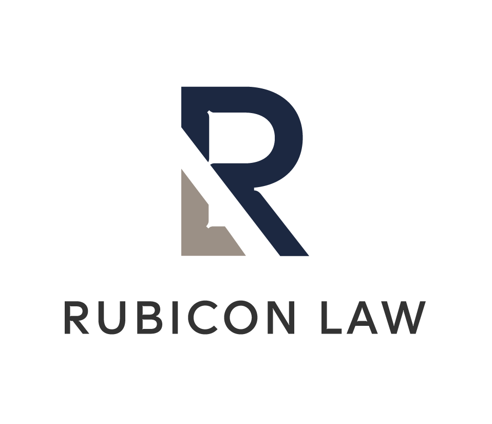 Logo of Rubicon Law featuring a stylized 'R' in navy blue and a light gray geometric shape, with the text 'RUBICON LAW' beneath it.